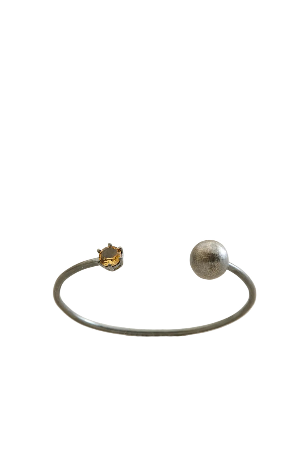 Silver bracelet with a spherical charm on a light beige background