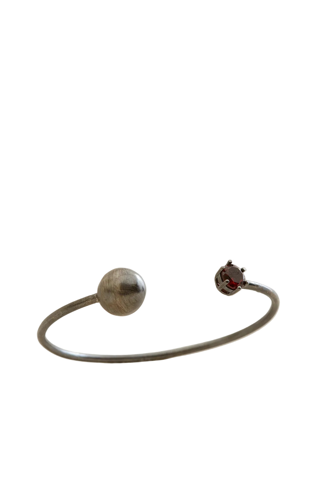 Silver bracelet with a round silver charm and a round red gemstone charm on a light beige background