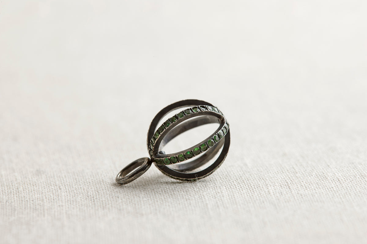 Silver ring with green gemstones on a light gray background
