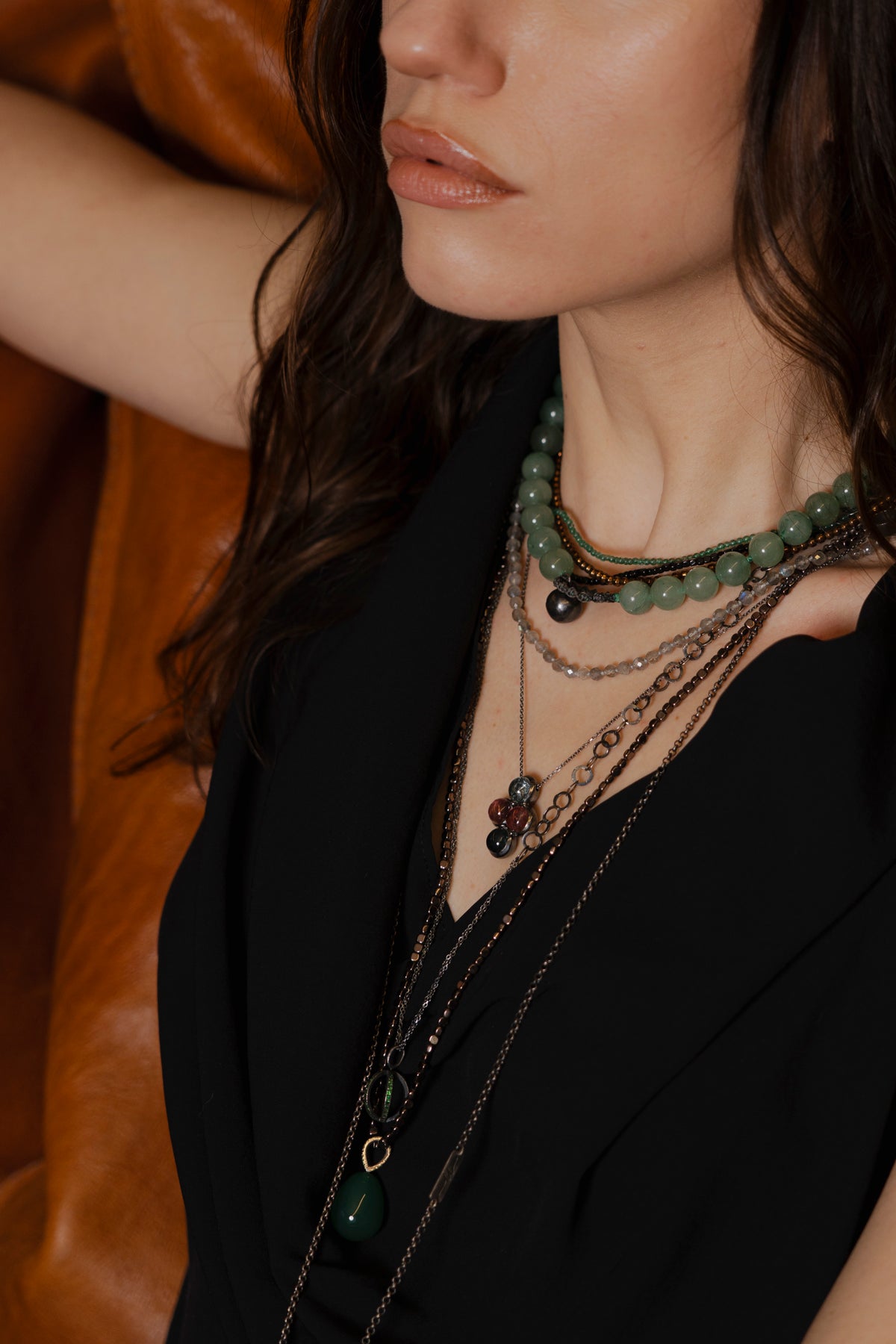 Close-up of a person wearing multiple necklaces with a blurred background
