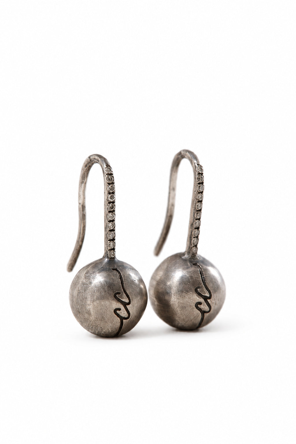 Pair of silver earrings with spherical designs on a light background