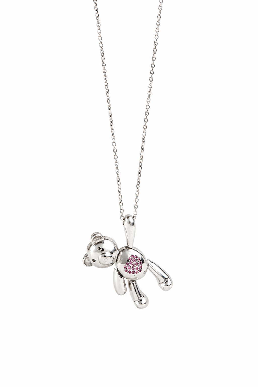 A silver teddy bear pendant necklace with a small pink heart-shaped gemstone on its chest, suspended from a delicate silver chain against a plain white background.