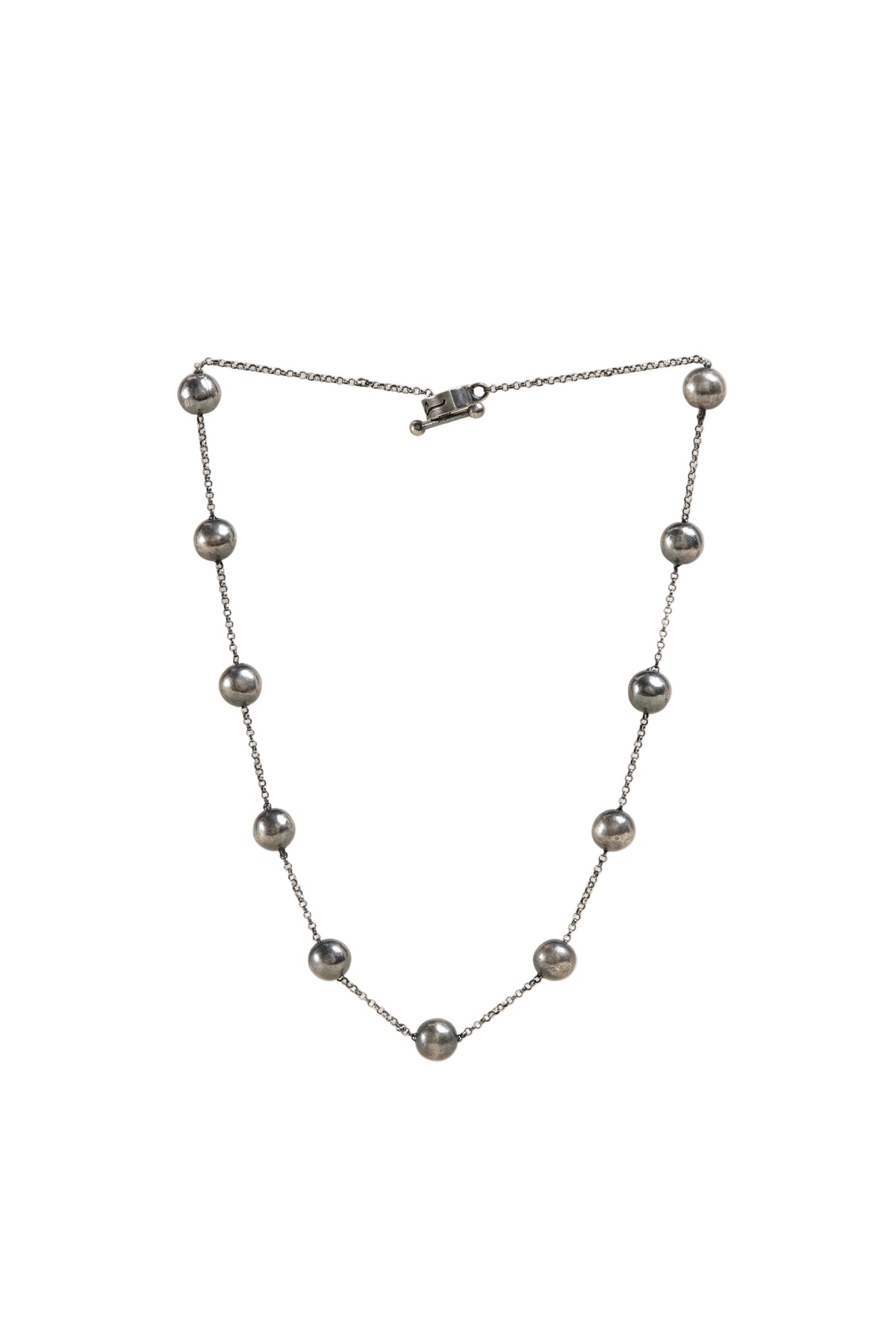 A silver-toned beaded necklace featuring nine small, evenly spaced round beads on a delicate chain, displayed against a solid white background.