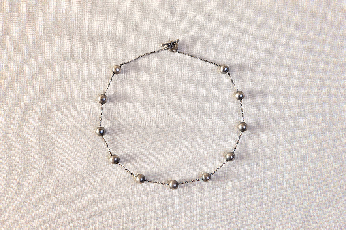 Silver bracelet with beads on a light gray background