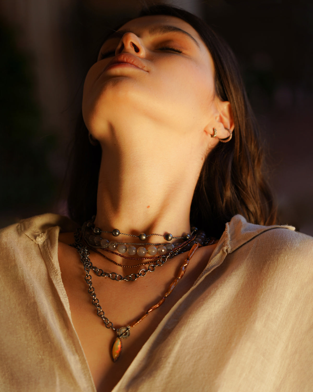 Close-up of a person wearing layered necklaces with a blurred background