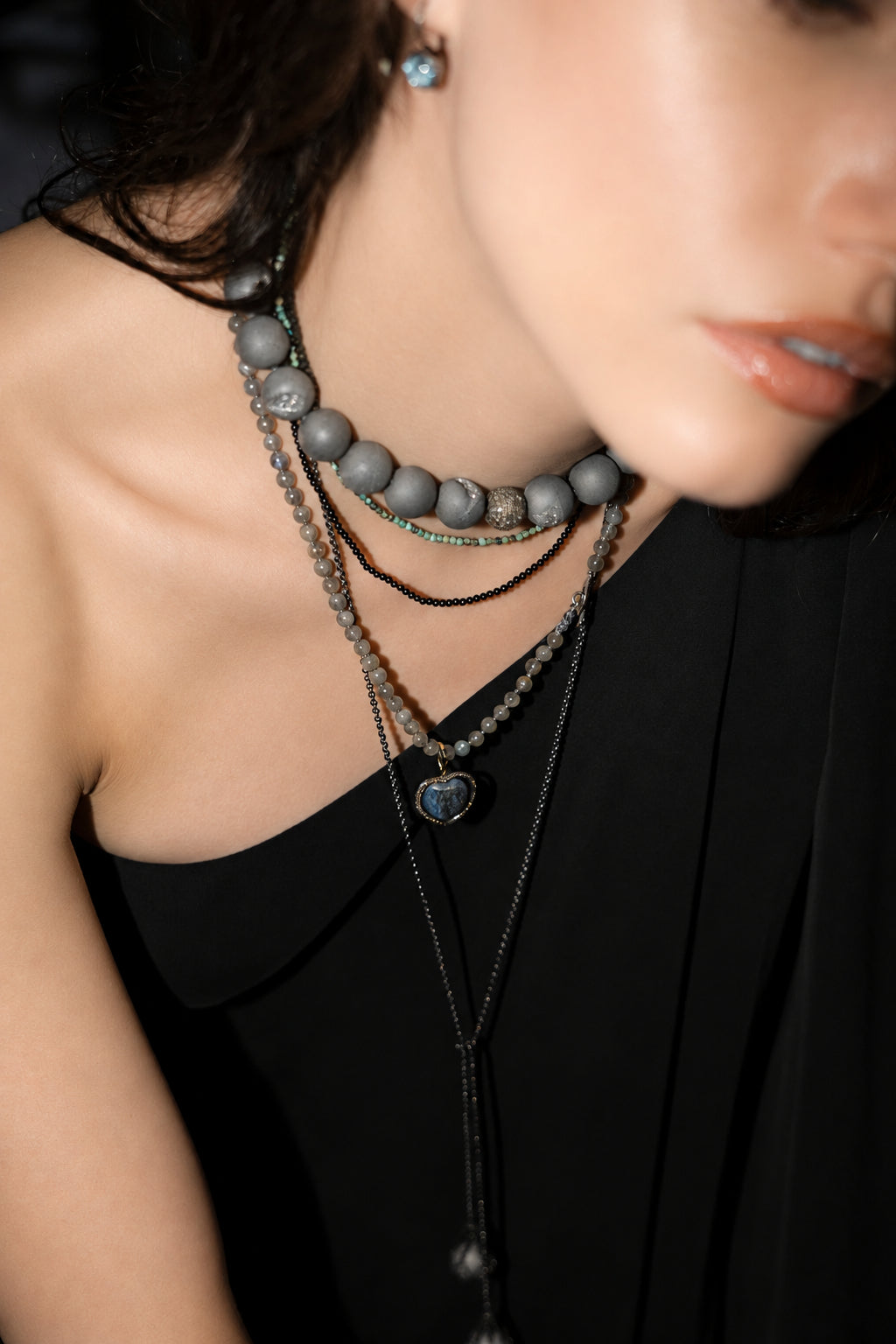 Close-up of a person wearing multiple necklaces with a blurred background