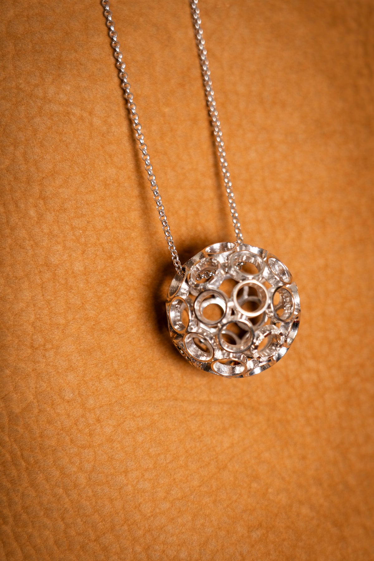 Silver necklace with a decorative pendant on a brown background