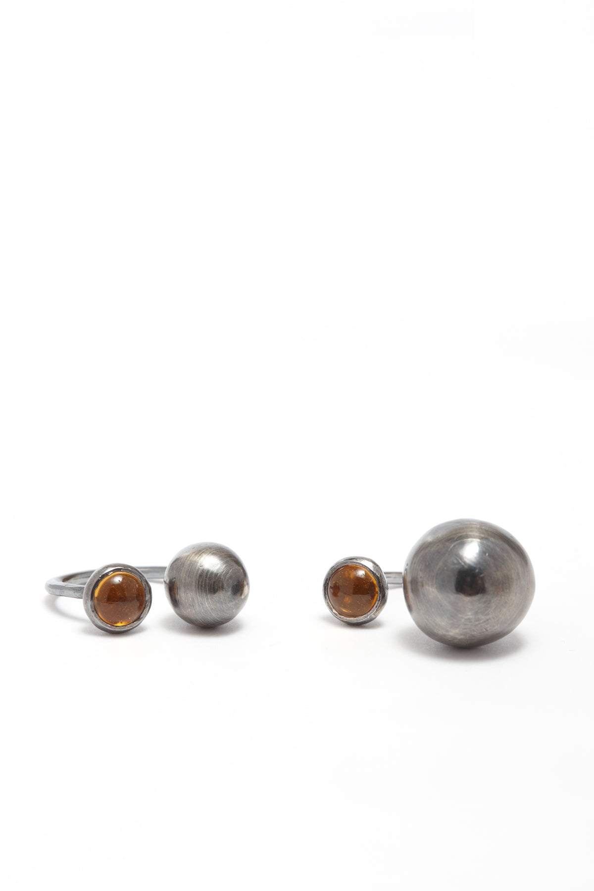 Set of three silver rings with brown gemstones on a white background