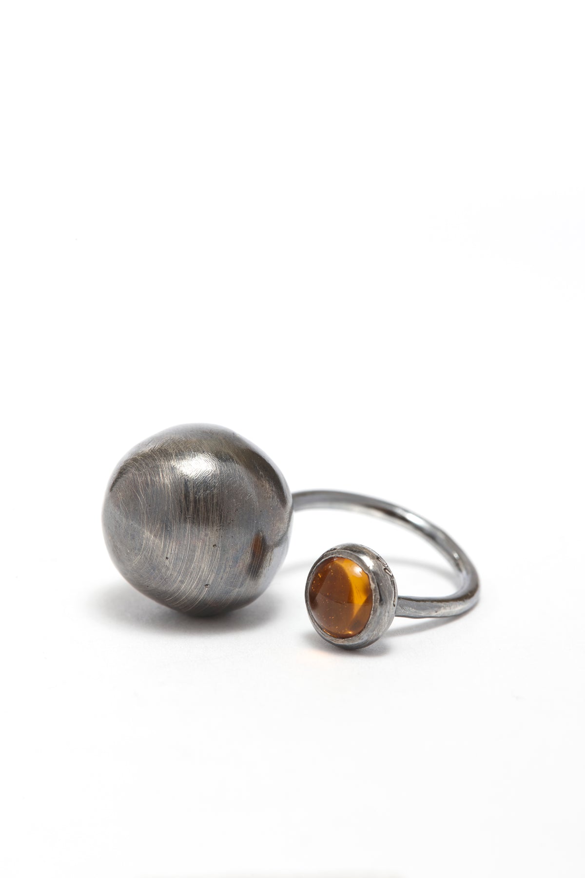Silver ring with a spherical silver end and amber gemstone on a white background