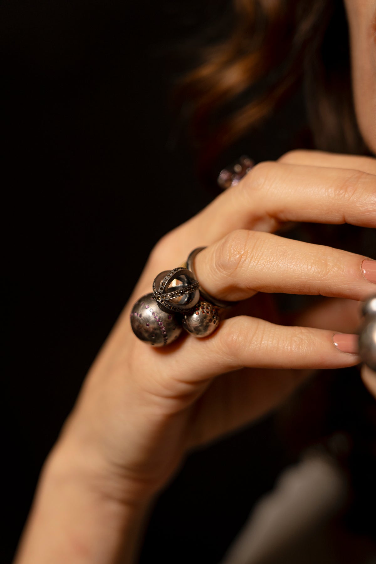 Close-up of a hand wearing multiple rings with a dark background