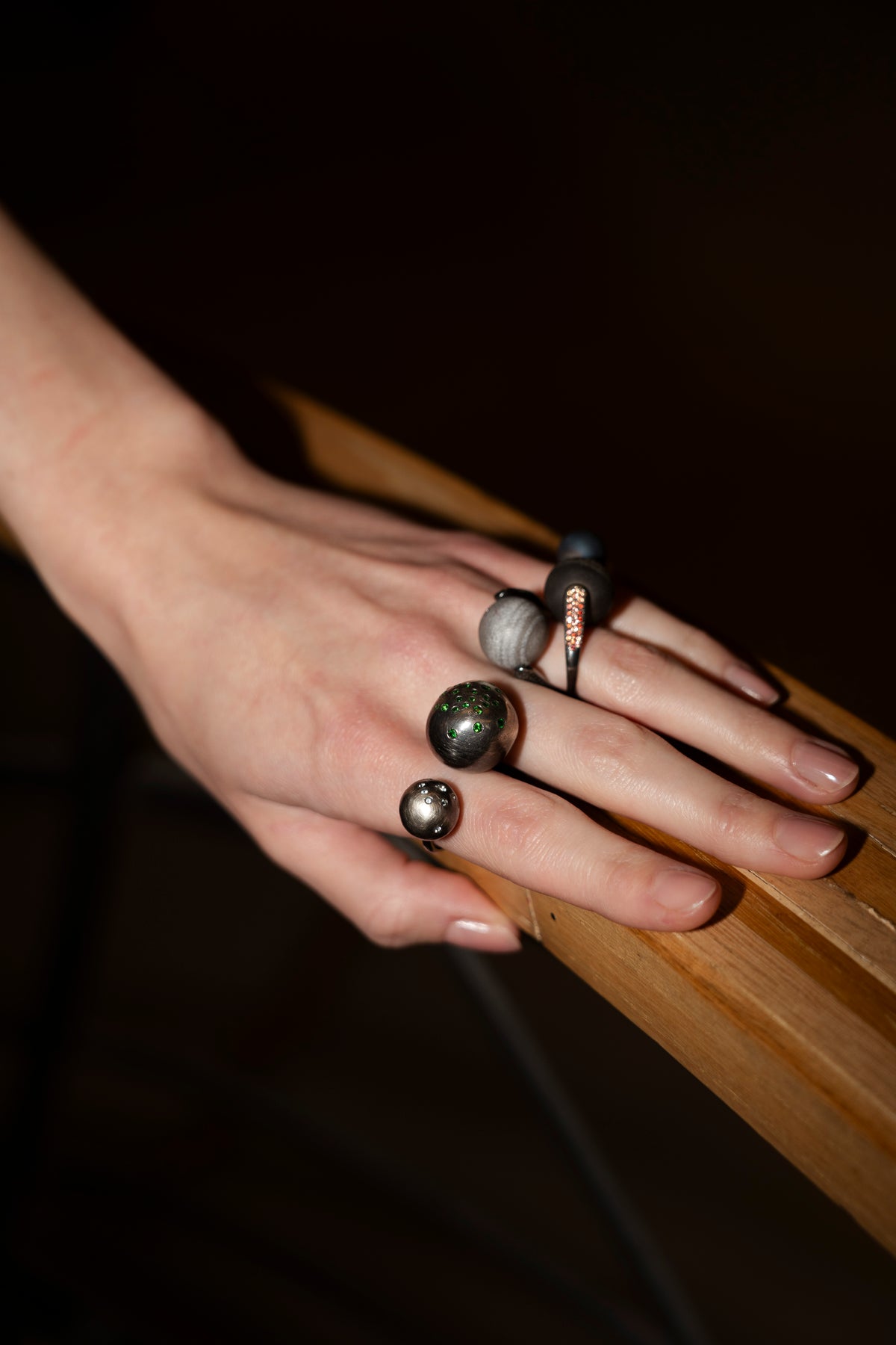 Hand wearing multiple rings on a dark background