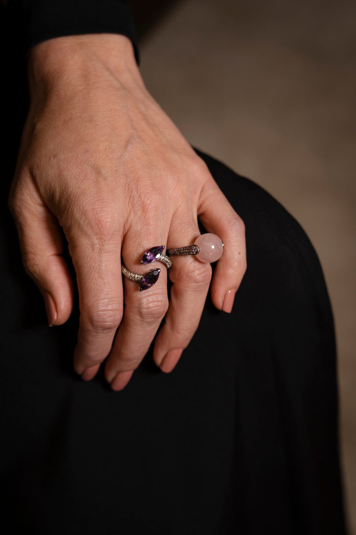 Close-up of a hand wearing multiple rings with a blurred background