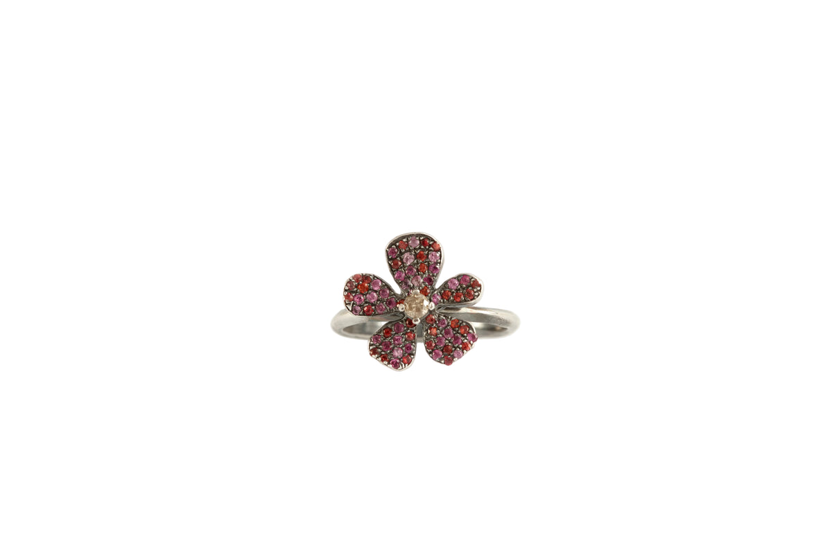 Flower-shaped ring with gemstones on a white background