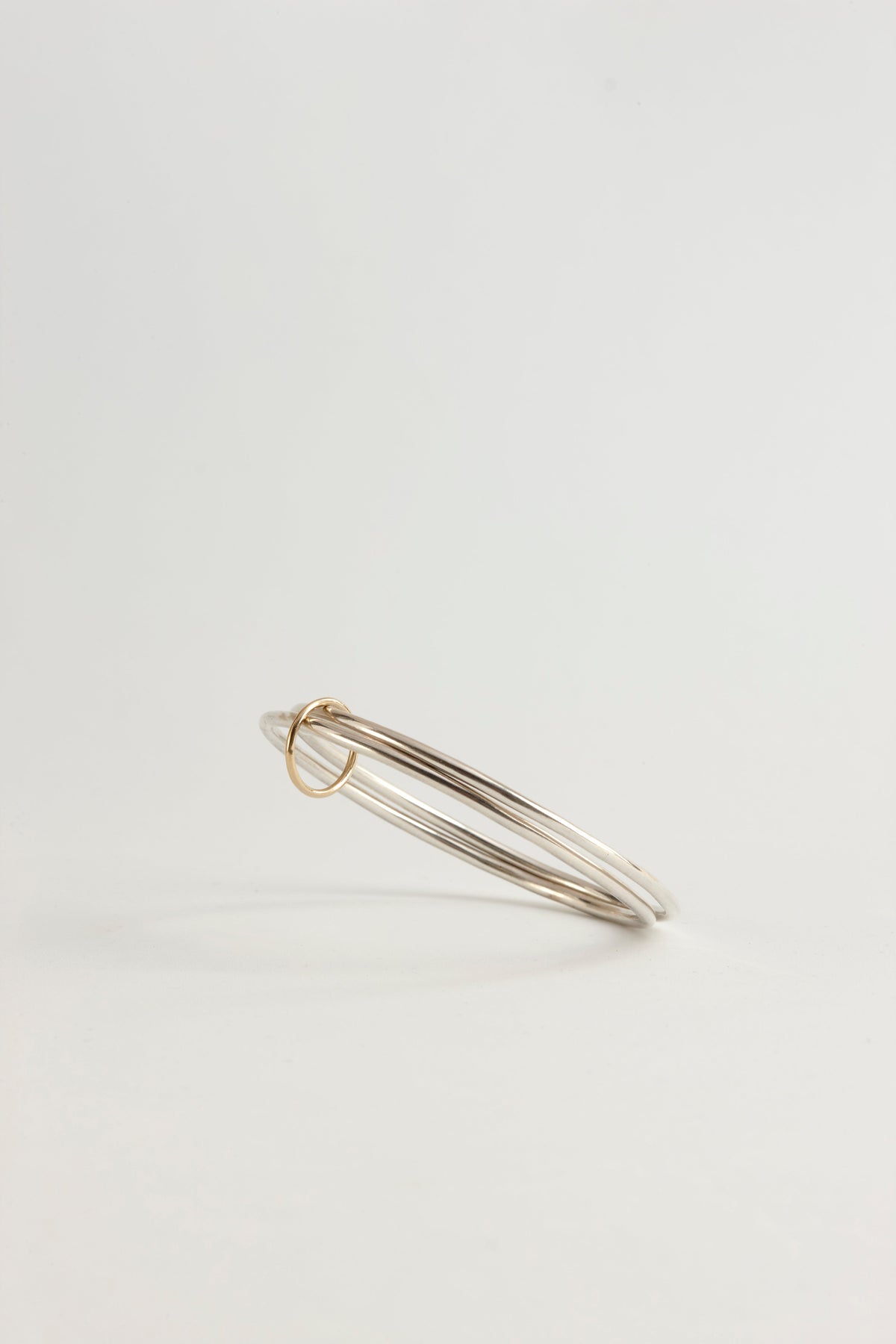 Cynthia Djurovic sterling silver bangles featuring a delicate 18k gold circle of life charm in a stacked design.