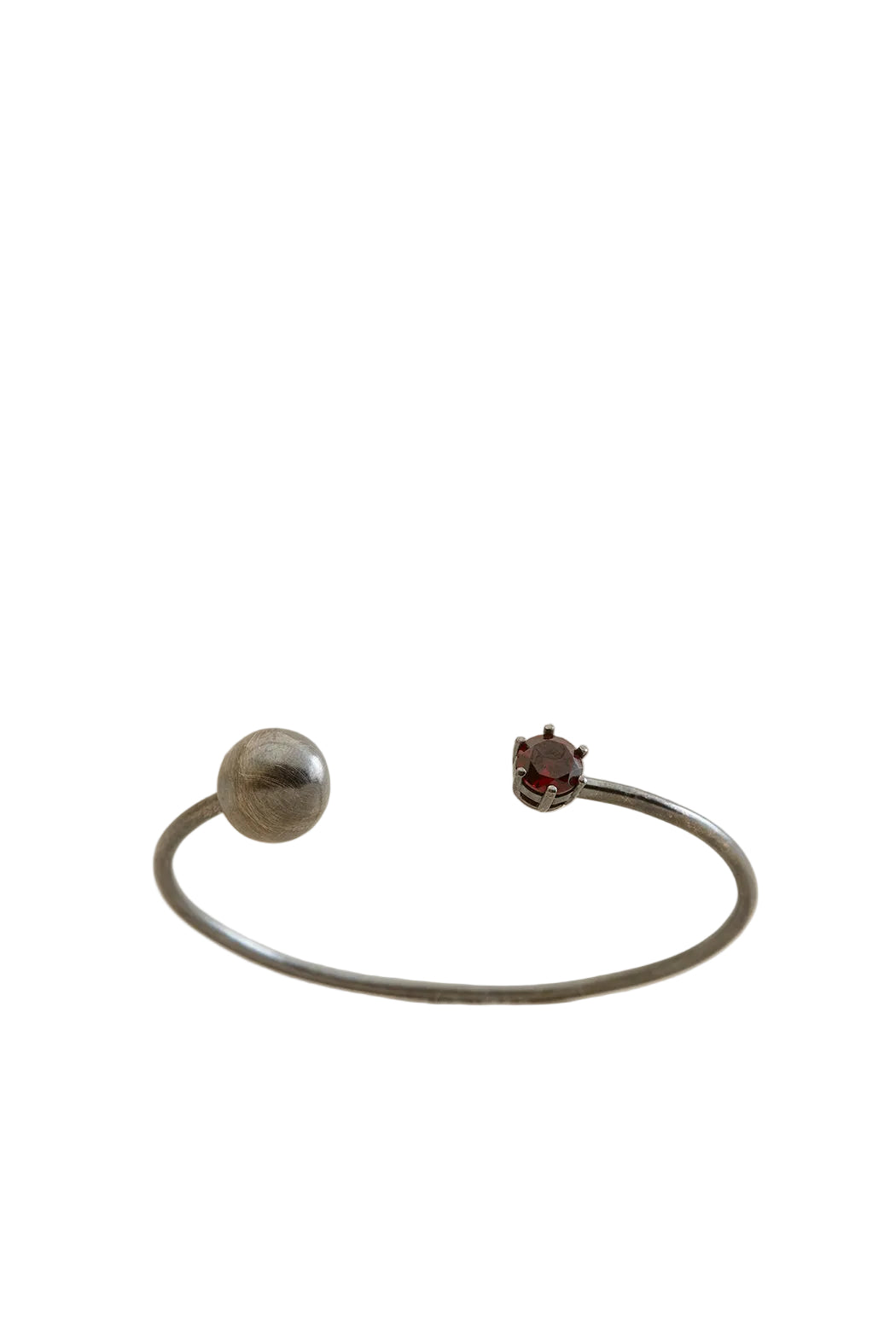 Silver bracelet with a round and a small round gemstone on a beige background