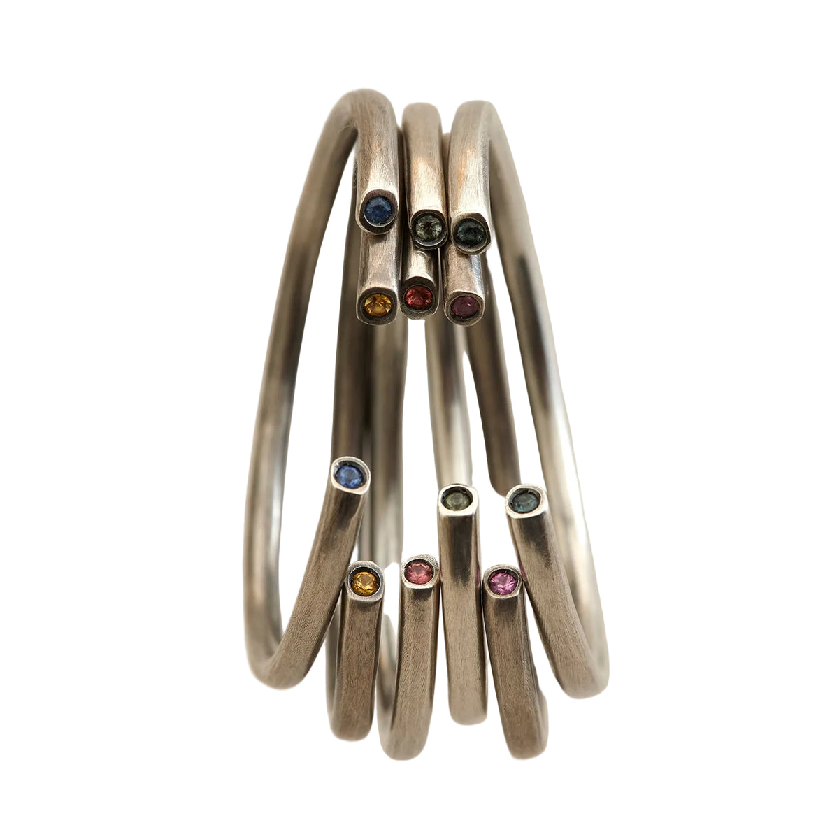 Set of silver bangles with colored stones on a beige background