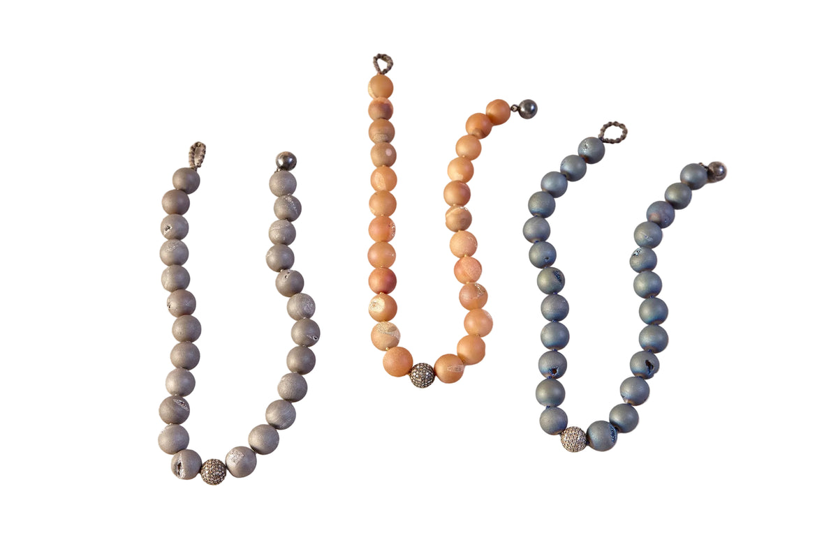 Four beaded necklaces of different colors on a light background