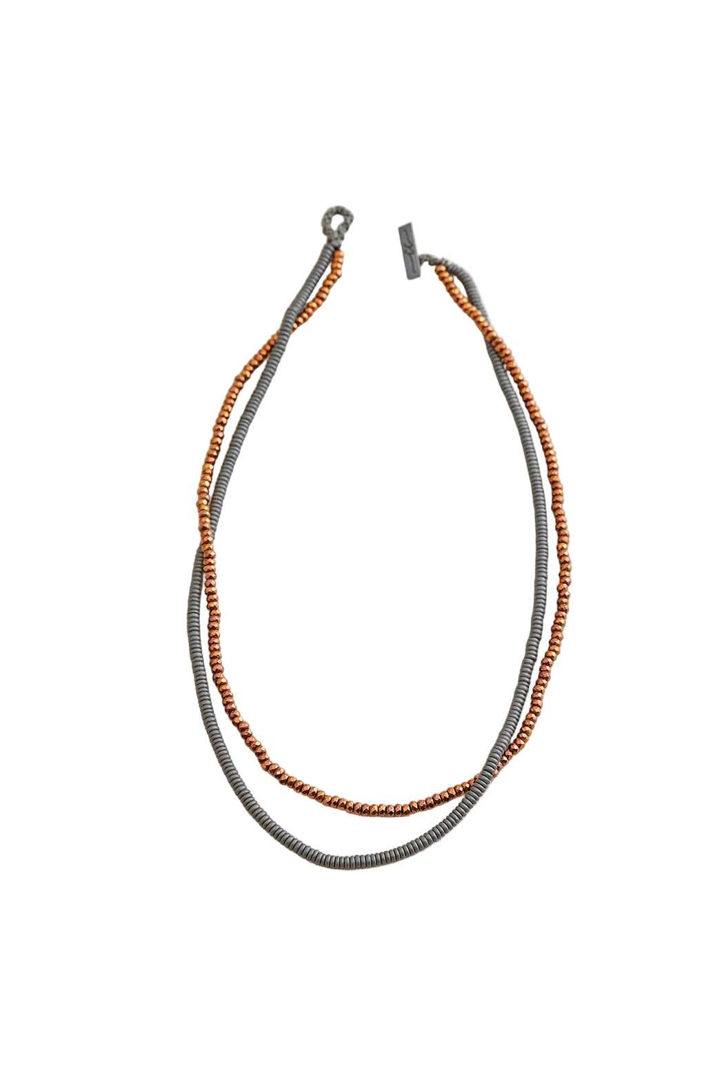 Two beaded necklaces, one gray and one brown, on a light beige fabric background.
