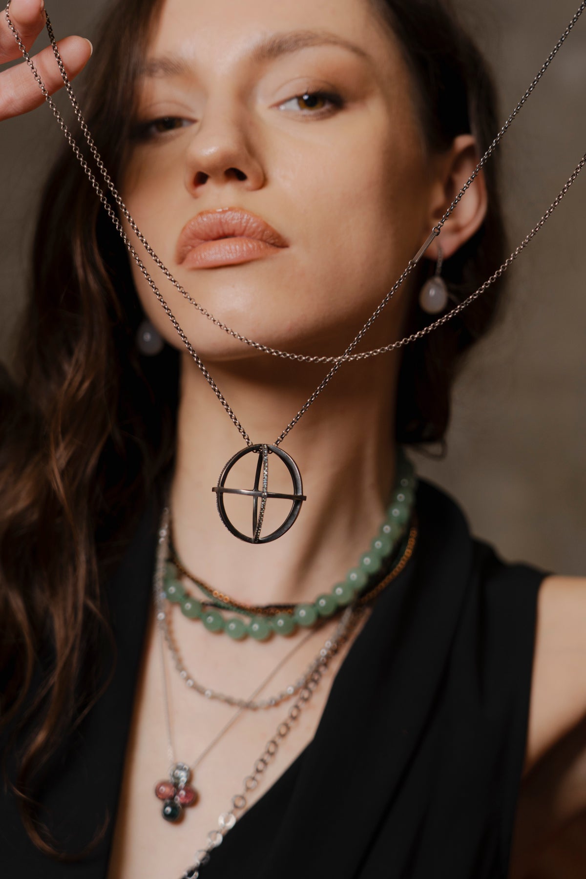 Woman wearing multiple necklaces with a neutral background