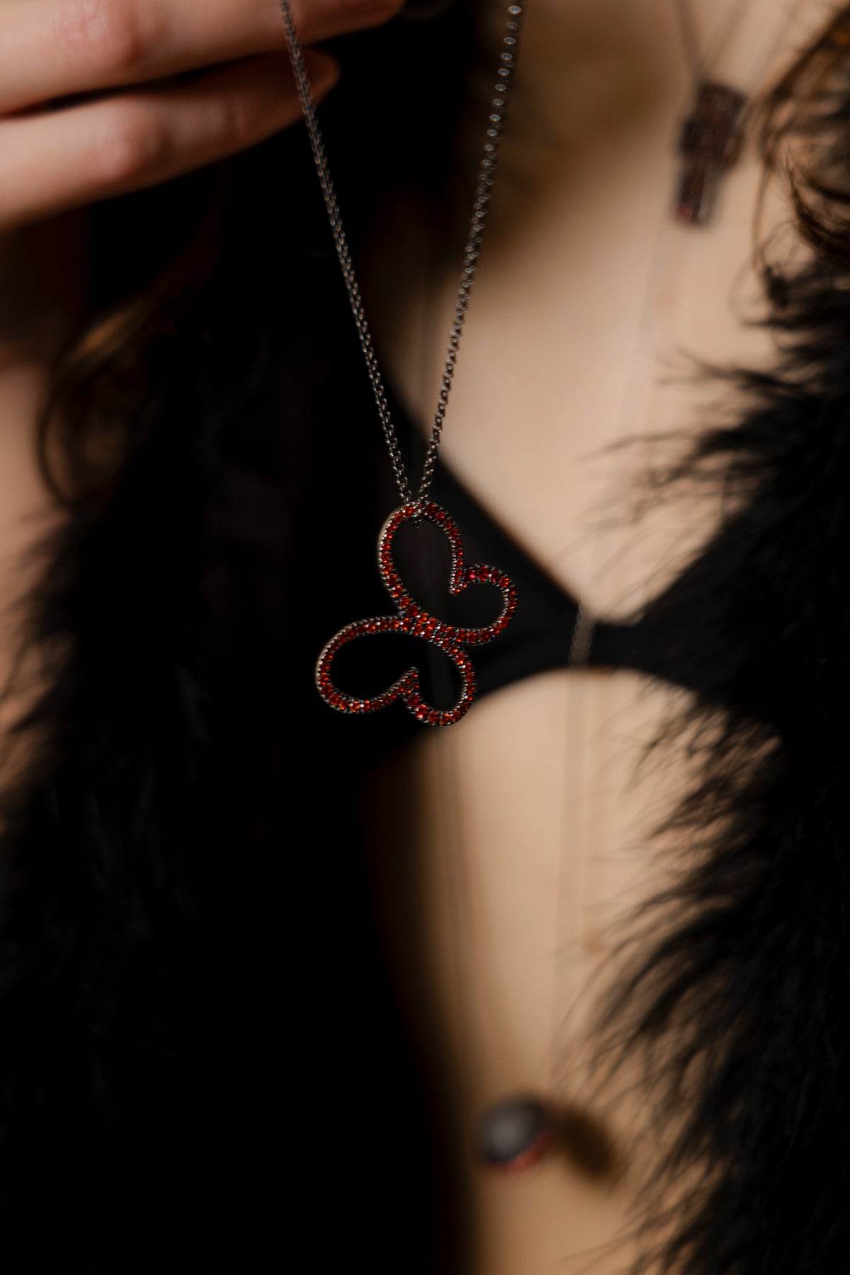 Necklace with a heart-shaped pendant worn by a person with dark hair.