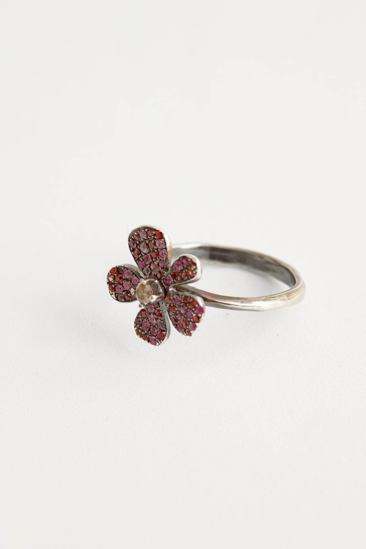 Flower-shaped ring with red gemstones on a white background